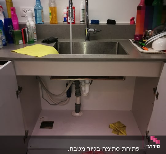 כיור מטבח עם ברז פתוח וצנרת גלויה מתחת